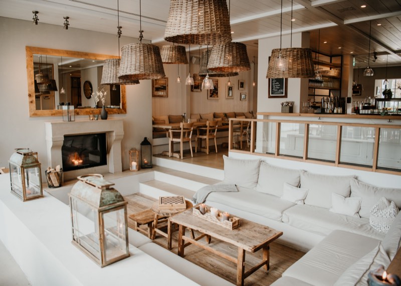 Hotellounge mit offenem Kamin, Laternen und Korbleuchten, Stufen führen hinauf zur Bar
